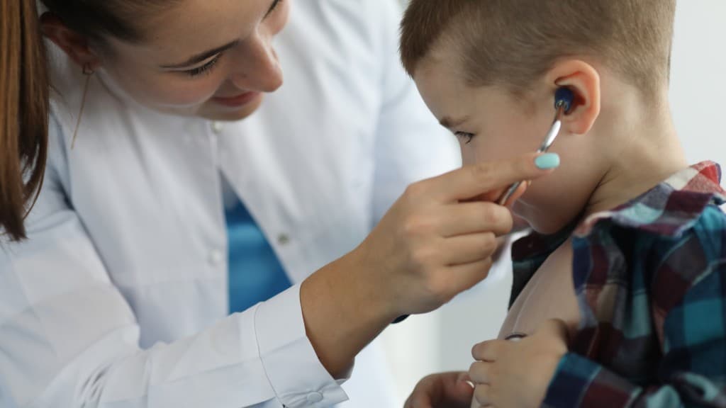 A paediatrician examining a child's ear during a calm clinic visit